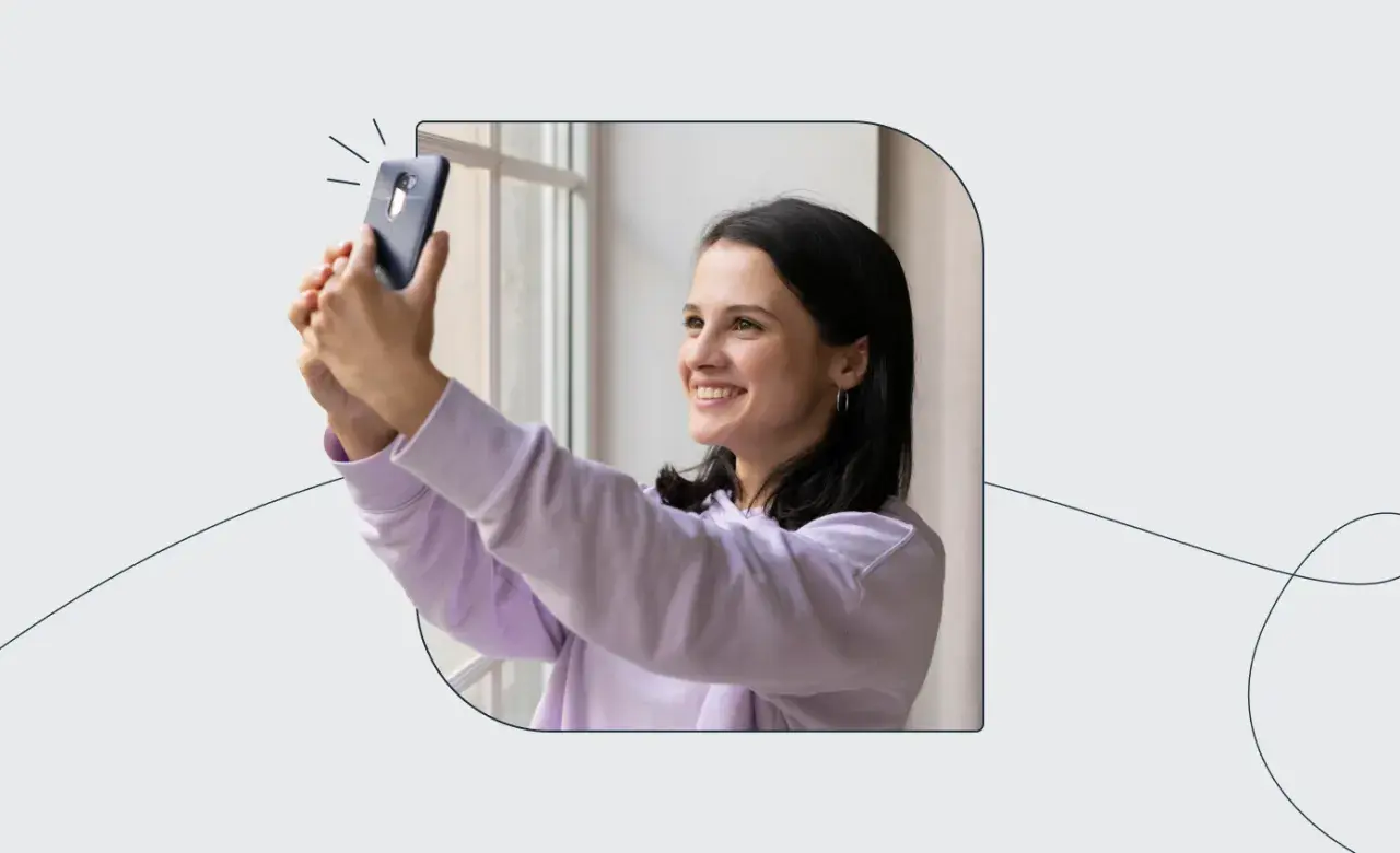 Uśmiechnięta dziewczyna robi selfie telefonem, ćwicząc, jak zrobić zdjęcie do dowodu.